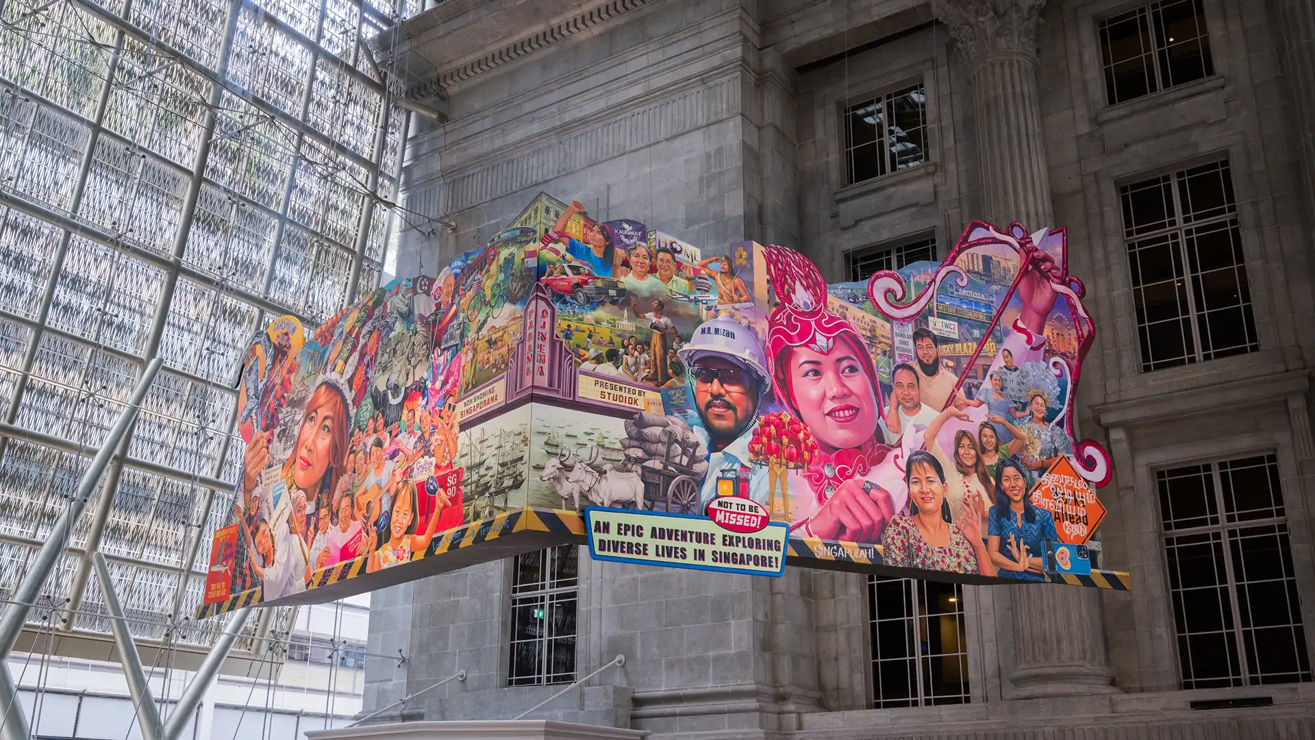 Colourful vintage-movie styled hanging art installation with many faces showing Singaporean culture and heritage